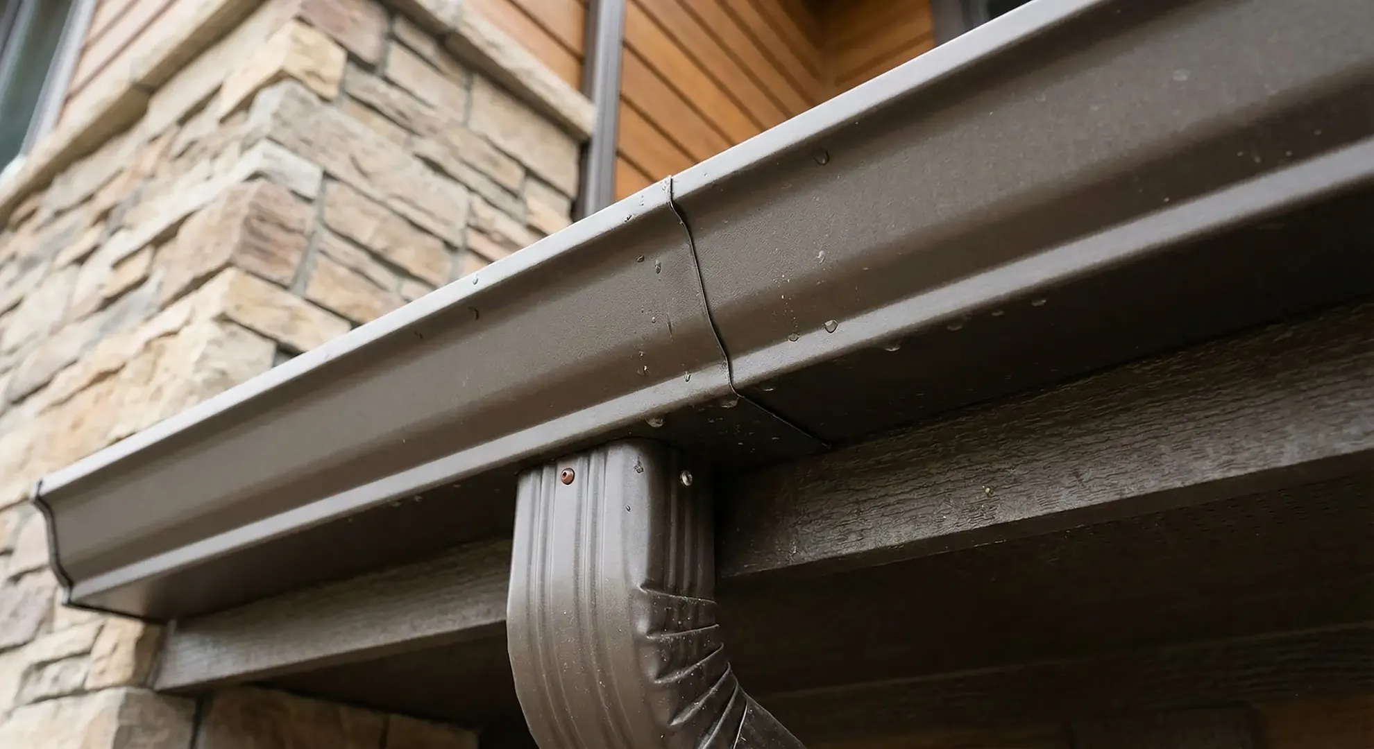 Seamless aluminum gutter and downspout at a roof edge